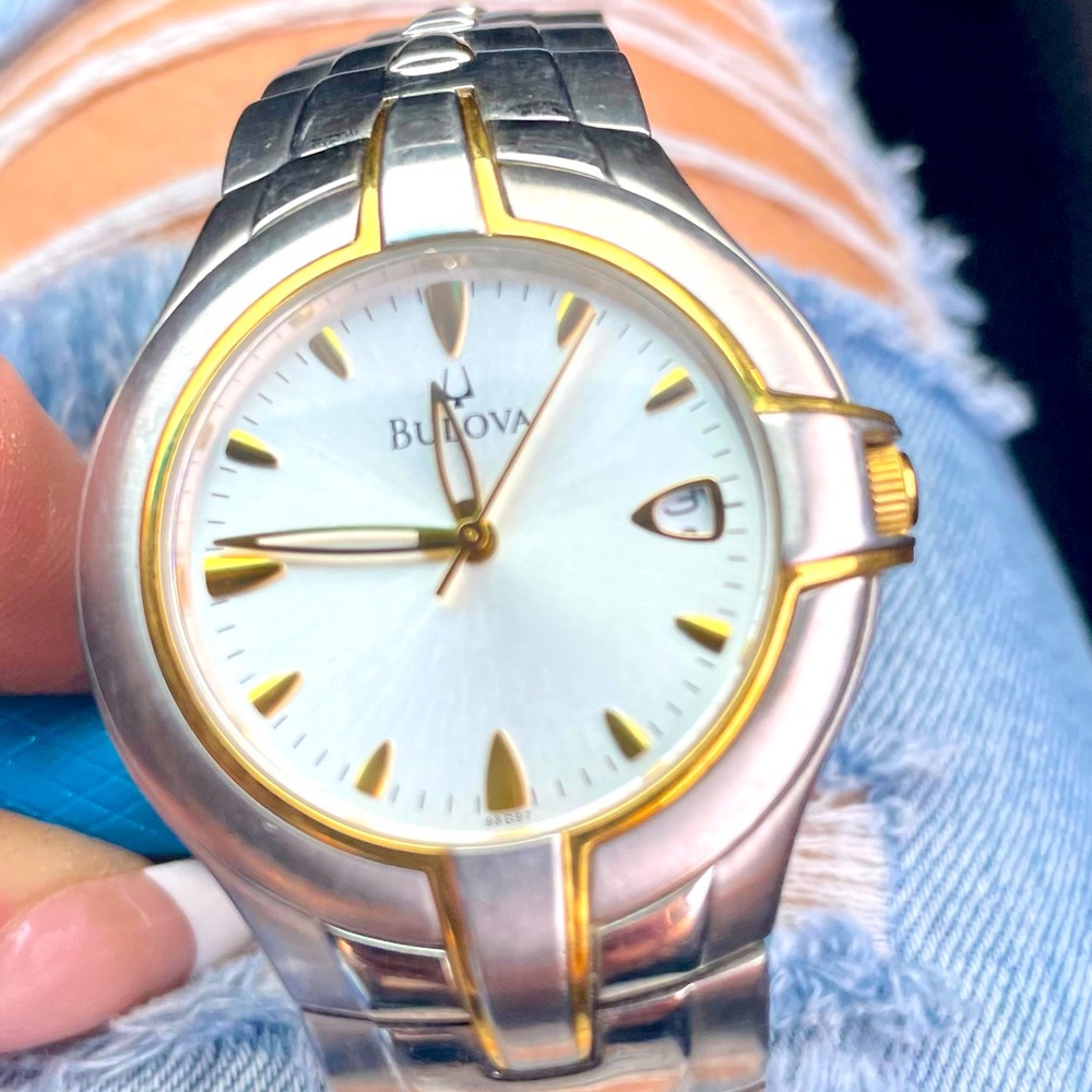 Stylish Bulova watch with gold and silver accents. Features a white dial.